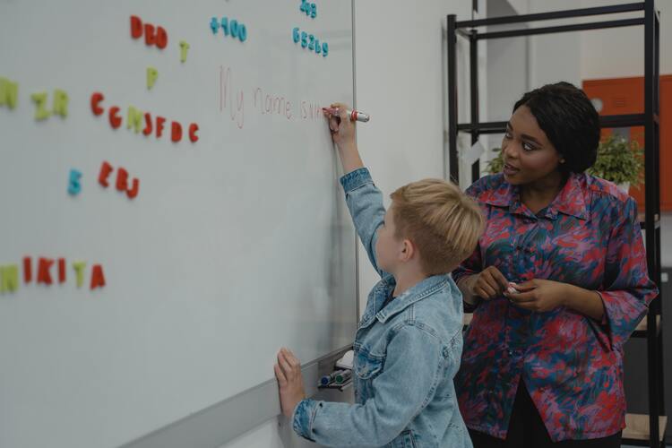 Teaching Assistant next to student writing on the board