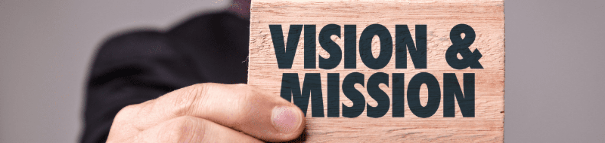 Man holding paper saying 'Vision' and 'Mission'